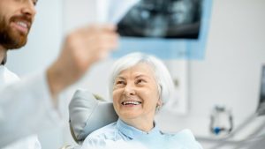 Dentist Showing Dental X-Ray To Senior Patient