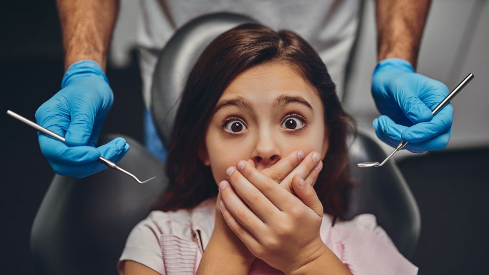 Anxious Girl Conceals Her Mouth With Hands, Fearful of a Dental Examination