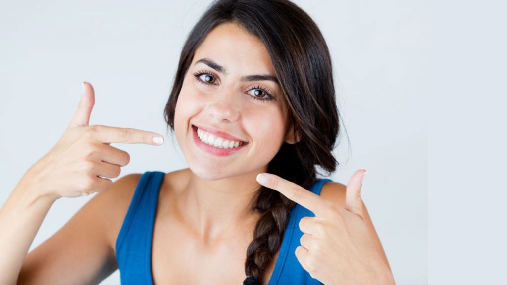Woman Smiling And Pointing At Her Teeth